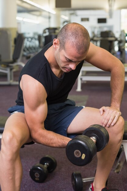 Young man exercising with dumbbell in gym