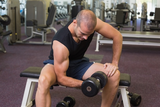 Young man exercising with dumbbell in gym