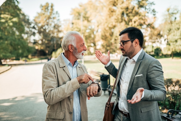 Young man explaining to dissatisfied senior man why he was late.