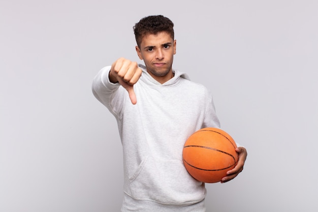 Young man feeling cross, angry, annoyed, disappointed or displeased, showing thumbs down with a serious look.