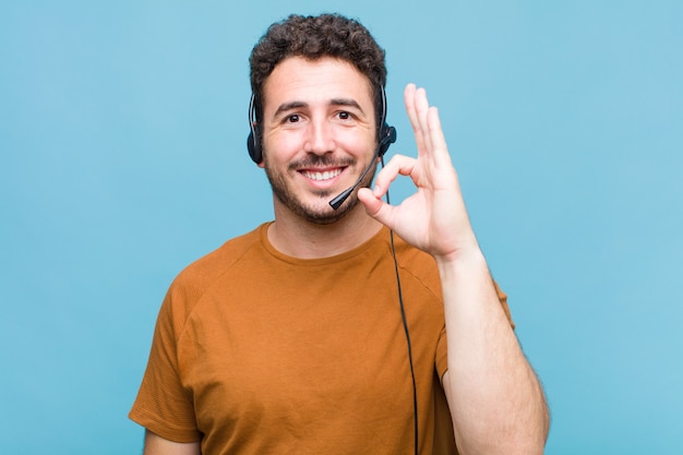 Young man feeling happy, relaxed and satisfied, showing approval with okay gesture, smiling