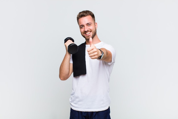 Young man feeling proud, carefree, confident and happy, smiling positively with thumbs up