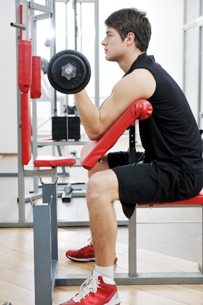 young man in fintess sport club exercise withweights and relaxing