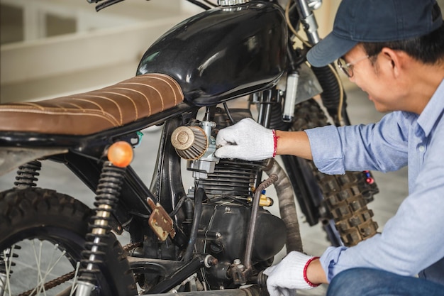 Young man fixing motorcycle in workshop garage Man repairing motorcycle in repair shop Mechanical hobby and repairs concepts