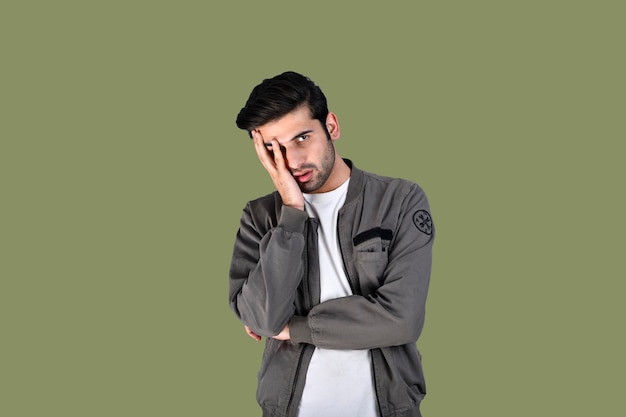 young man front pose wearing jacket hand on face green background indian pakistani model