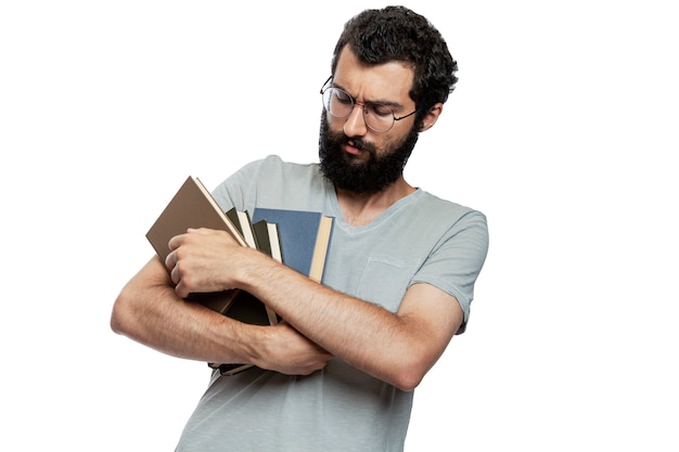 A young man in glasses and with a beard with books in his hands with emotion on his face. Education and training. Isolated.