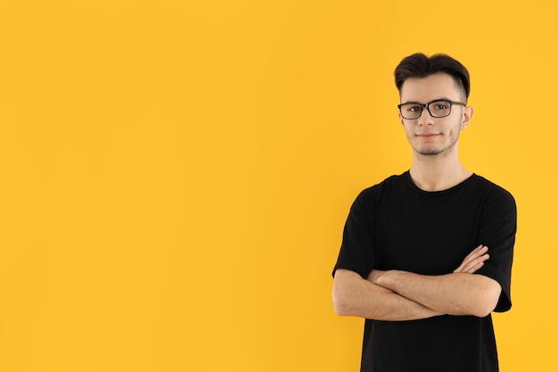 Young man in glasses on yellow background