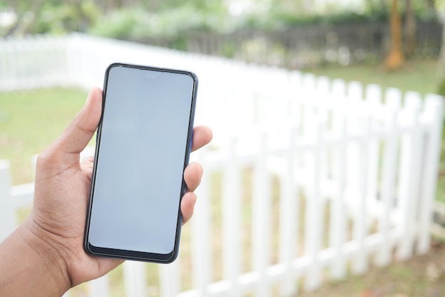 Young man hand using smart phone with green screen against city buildings