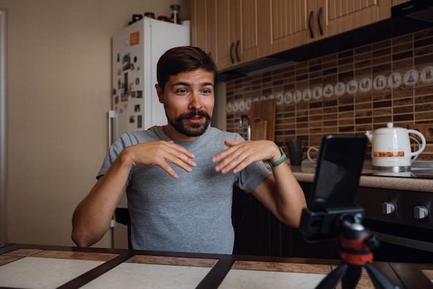 Young man having video call via smartphone in the home office