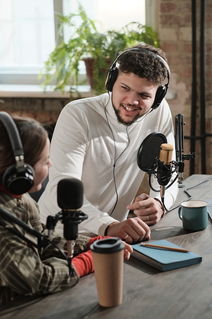 Young man in headphones interviewing the woman during air on the radio