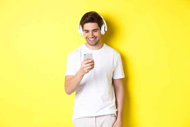 Young man in headphones reading message on smartphone