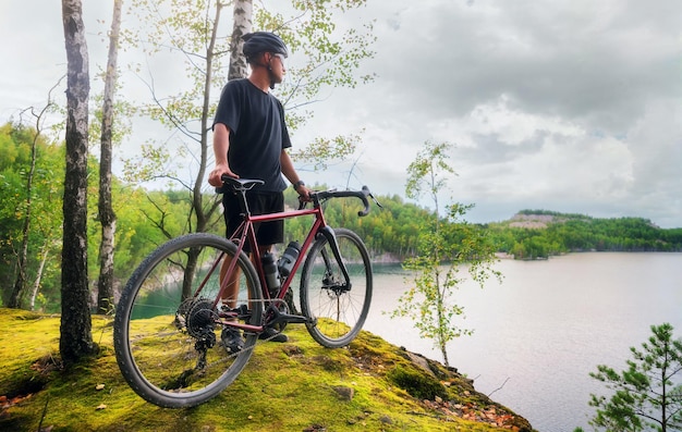 Young man in a helmet stands with a bicycle on the edge of a cliff Sports and travel