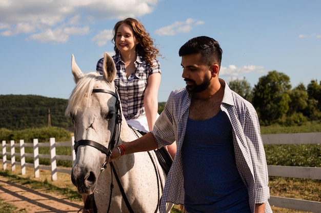 The young man helps a woman to ride a horse