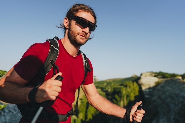 Young man hiker travels through the mountains with trekking poles for nordic walking