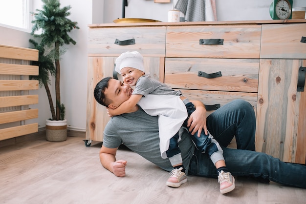 Young man and his son playing in the kitchen