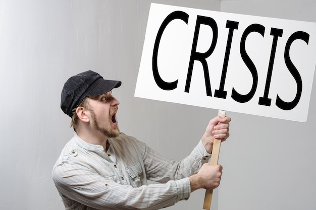 Photo young man holding a banner with crisis inscription