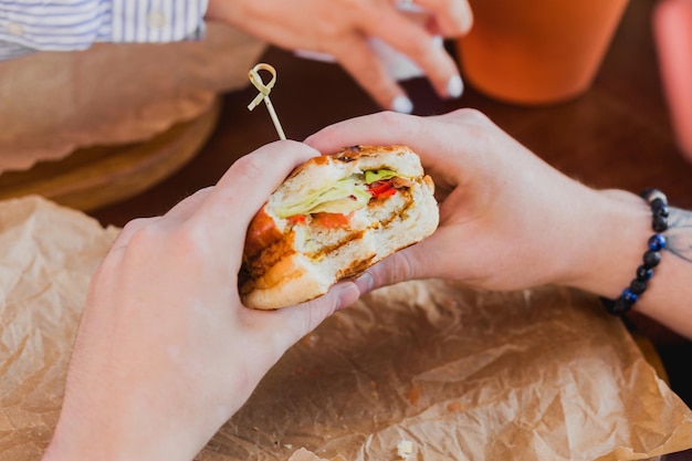 Young man holding a bitten burger in his hands Fast food in a cafe