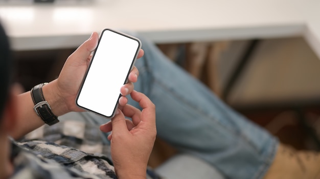 Young man holding blank screen smartphone  with relax sitting position