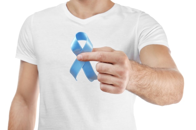 Young man holding blue ribbon on white. Cancer awareness concept