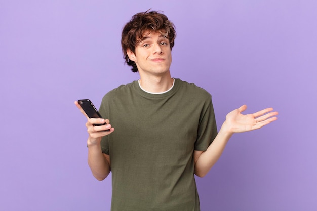 Young man holding a cell feeling puzzled and confused and doubting