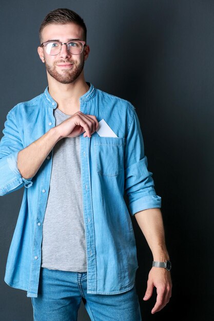 Young man holding a credit card standing on gray background Young entrepreneur