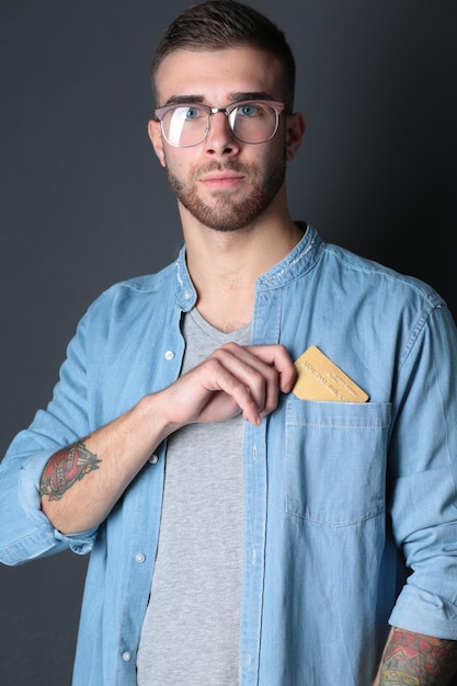 Young man holding a credit card standing on gray background Young entrepreneur