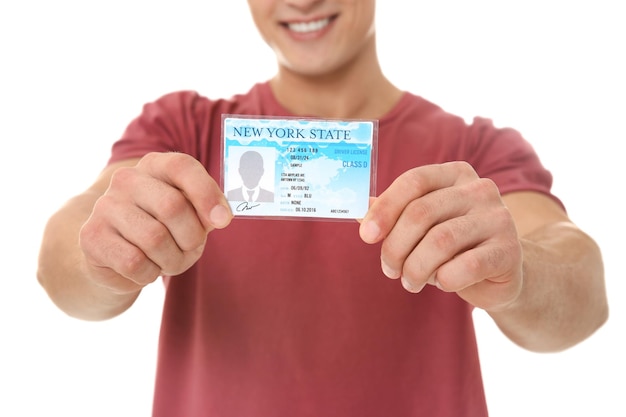 Young man holding driving license on white background