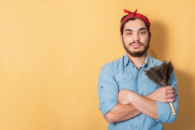 Young man holding a feather duster supporting the feminist movement