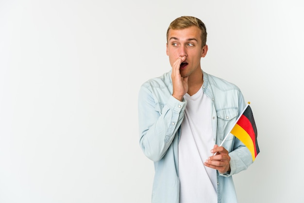 Young man holding a german flag and telling a secret