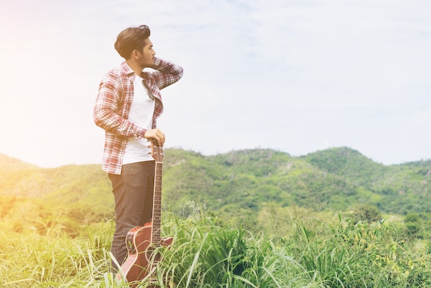 Young man holding guitar in mountain view