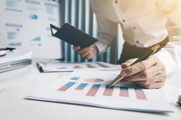 Young man holding a pen analysis financial data in office room.