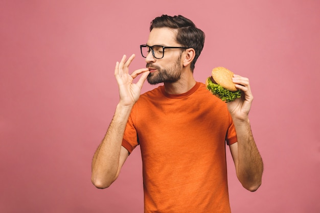 Young man holding a piece of hamburger. Student eats fast food. Burger is not helpful food. Very hungry guy. Diet concept.