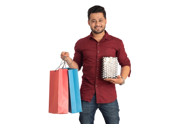 Young man holding and posing with shopping bags and gift boxes on a white background