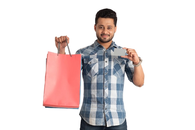 Young man holding and posing with shopping bags with credit or debit card on a white background