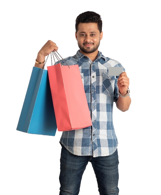 Young man holding and posing with shopping bags with credit or debit card on a white background