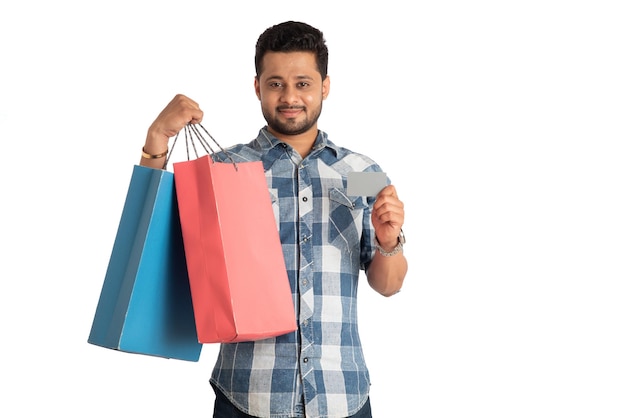 Young man holding and posing with shopping bags with credit or debit card on a white background