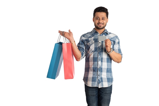 Young man holding and posing with shopping bags with credit or debit card on a white background