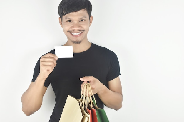 Young man holding shopping bag with blank card Consumerism shopping lifestyle concept