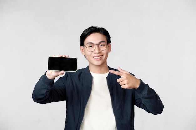 Young man holding smartphone in his hand and pointing his finger on blank screen