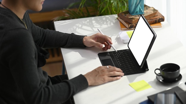 Young man holding stylus pen and using computer tablet working online at home.