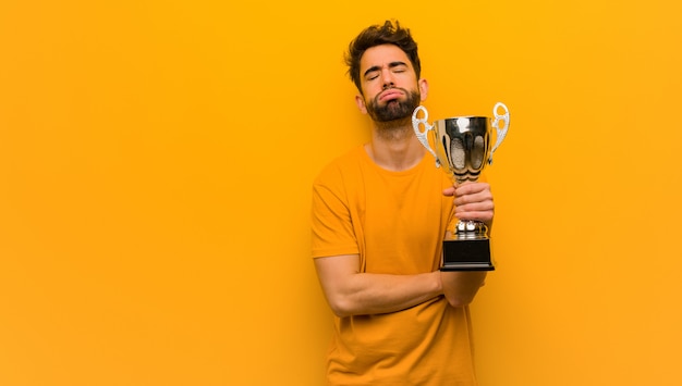 Photo young man holding a trophy tired and bored