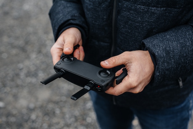 A young man holds a remote control for controlling a copter.