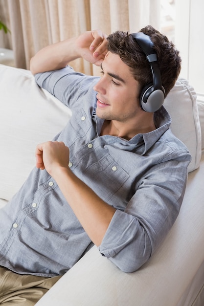 Young man at home relaxing on the sofa listening to music