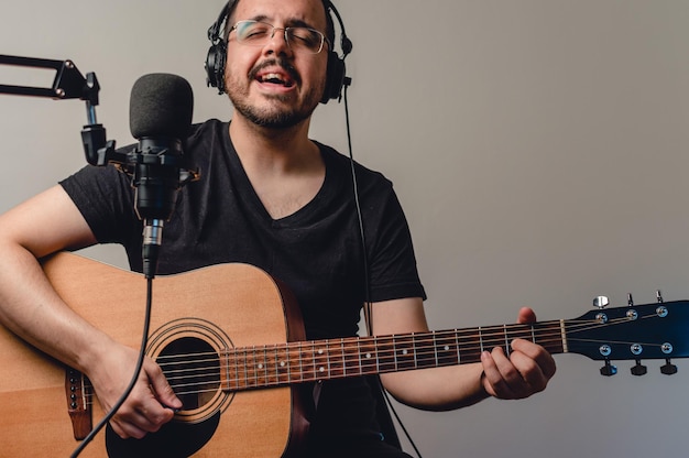 Young man in home studio singing and playing acoustic guitar streaming