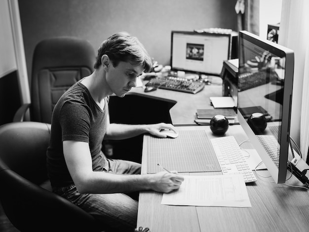 Young man at home using a computer, freelance developer and designer working at home, black and white photo