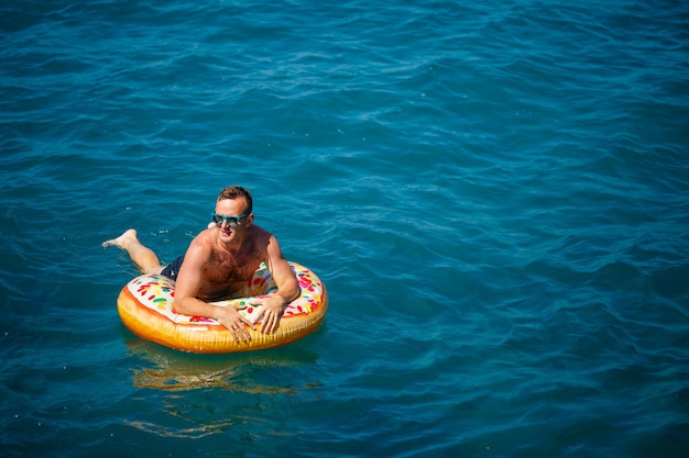 Young man on an inflatable ring in the sea resting and swimming on a sunny day