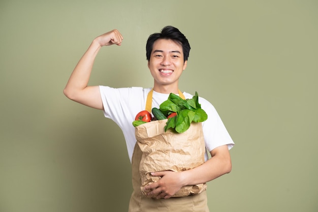 Young man is holding a bag full of vegetables on white background