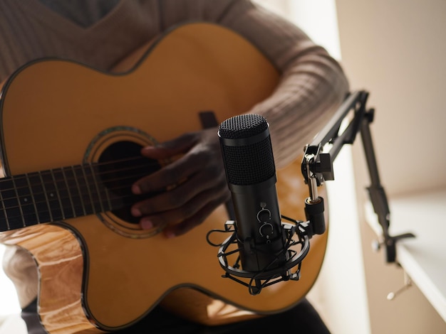 Young man is singing and playing guitar while making an audio recording at home