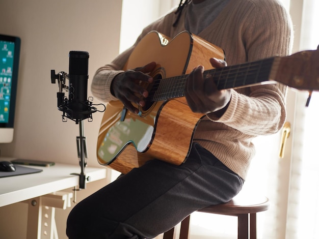 Young man is singing and playing guitar while making an audio recording at home