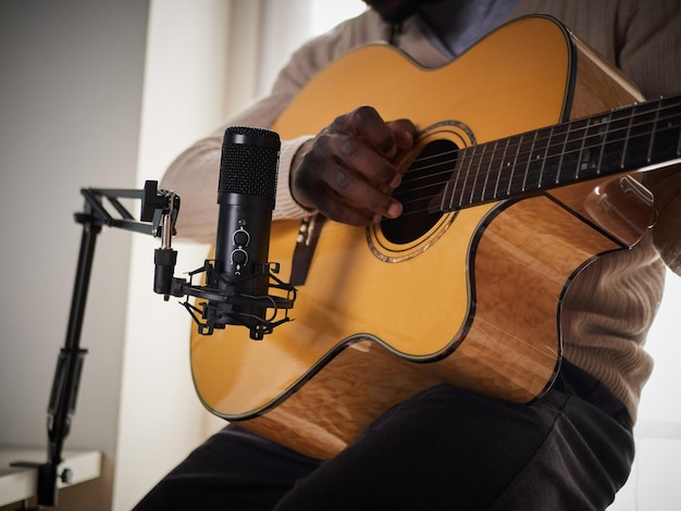 Young man is singing and playing guitar while making an audio recording at home